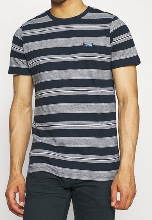 Homme portant un t-shirt à manches courtes rayé horizontalement bleu marine et gris avec un petit logo rectangulaire sur la poitrine.
