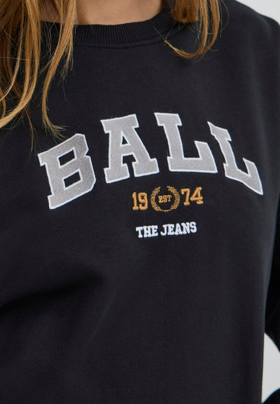 Fekete pamut pulóver, amelyen nagy szürke betűkkel szerepel a "BALL" felirat, a kisebb szövegek között pedig "1974 EST" és "THE JEANS" található, fehér és arany színű kiemeléssel.