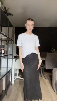 Melnas mežģīņu maksi svārki ar pieguļošu siluetu, ko apvieno ar vienkāršu baltu T-kreklu. Gluda tekstūra un sarežģītas mežģīņu rakstu detaļas.