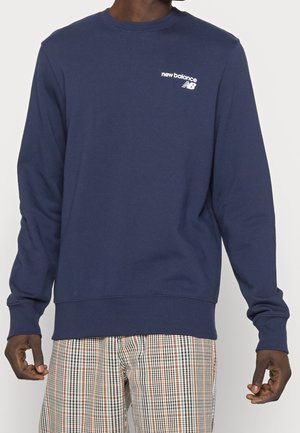 Sudadera de color azul marino hecha de una mezcla de algodón, con mangas largas, cuello redondo y logo en blanco de "new balance" en el pecho.