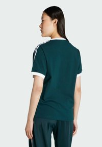 Teal cotton T-shirt featuring white collar and sleeve accents, with three white stripes along the shoulders and a round neck design.