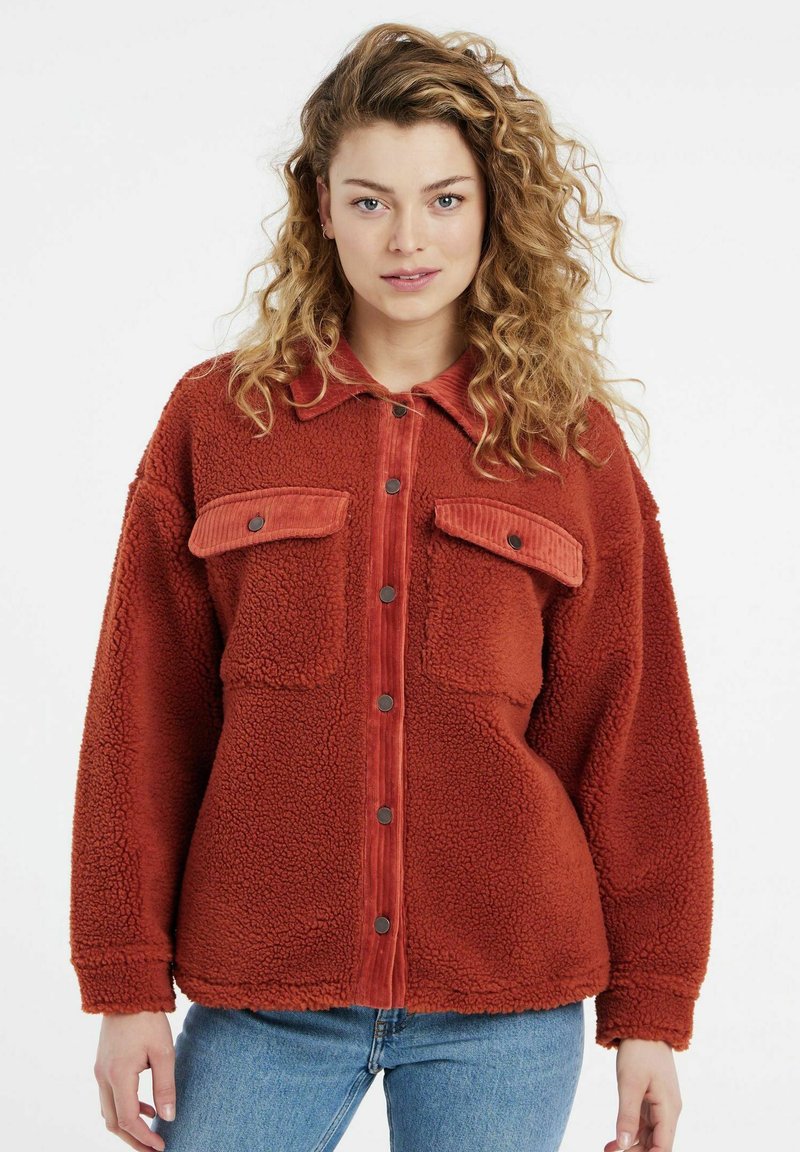Rust-colored fleece jacket with corduroy accents, featuring a button-front, two chest pockets, and textured, plush fabric.