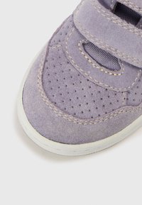 Baskets en daim violet avec des bandes auto-agrippantes, côté perforé pour la respirabilité, et semelle en caoutchouc blanche. Présente des coutures contrastantes.