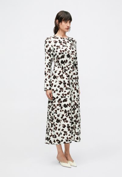 Šaty s dlhým rukávom v bielej farbe s čierno-hnedým kvetinovým vzorom, vybavené opaskom v páse, strihom do áčka a mierne lesklou látkou; doplnené špicatými lodičkami.