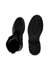 Zwarte leren laarzen met een gestructureerde afwerking, voorzien van metalen oogjes, vetersluiting en een stevige rubberen zool met een patroon.