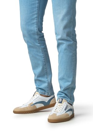 Weiße und blaue Turnschuhe mit Wildledereinsätzen, Gummisohlen und strukturierten Details, kombiniert mit eng geschnittenen hellblauen Jeans.