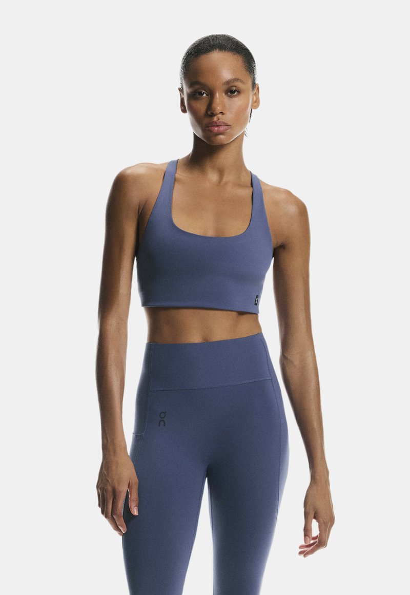 Sujeción deportiva y leggings de cintura alta en un tejido azul oscuro sólido. Ambos tienen una textura suave y un diseño minimalista con una sutil marca.