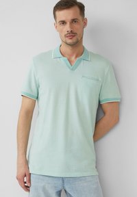 Lichtblauwe katoenen polo met een V-hals, korte mouwen en een borstzak. Bevat contrasterende bies langs de kraag en de mouwen.