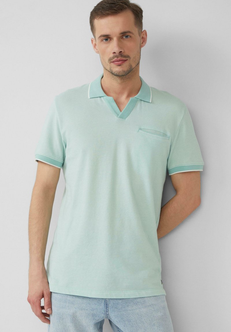 Lichtblauwe katoenen polo met een V-hals, korte mouwen en een borstzak. Bevat contrasterende bies langs de kraag en de mouwen.