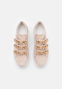 Beżowe zamszowe sneakersy z trzema dekoracyjnymi paskami z złotymi akcentami. Biała podeszwa, okrągły czubek i gładka faktura.