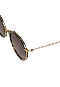 Pyöreät aurinkolasit ruskeilla tummennetuilla linsseillä, kultaisilla metalliosilla ja kilpikonnakuosisilla kehyksillä. Ominaisuuksiin kuuluvat ohuet sankaset ja hillitty brändäys.