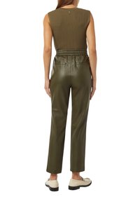 Haut côtelé vert olive avec un col rond, associé à un pantalon en cuir olive avec une taille élastique et des poches latérales.