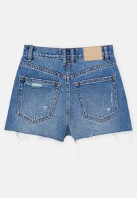 Bermudas de mezclilla en un color azul desgastado, con dobladillos deshilachados, dos bolsillos traseros y un parche de cuero rectangular en la cinturilla.