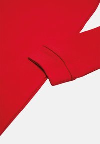 Sudadera roja con manga larga y una textura suave y lisa, con costuras en contraste a lo largo de los puños. Diseño simple y minimalista.