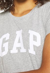 Šedé bavlněné tričko se výrazným bílým logem "GAP", kulatým výstřihem, krátkými rukávy a volným střihem.