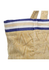 Tote bag van gestructureerde gele stof, met reliëfletters. De bovenkant heeft donkerblauwe en lichtbeige strepen, met twee stevige stoffen hengsels.