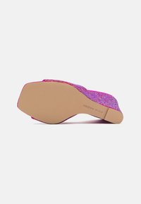 Chaussure à talon compensé texturée rose et violette avec une semelle beige lisse et un logo subtil en dessous.