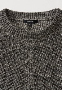 Schwarz-weißer Strickpullover mit gerippter Textur, Rundhalsausschnitt und sichtbarem Etikett mit der Aufschrift "OPUS 36" am Kragen.