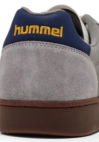 Suède grijze sneaker met een blauwe accent en gouden "hummel" logo. Bevat een gestructureerde bruine rubberen zool en contrasterende stiksels.
