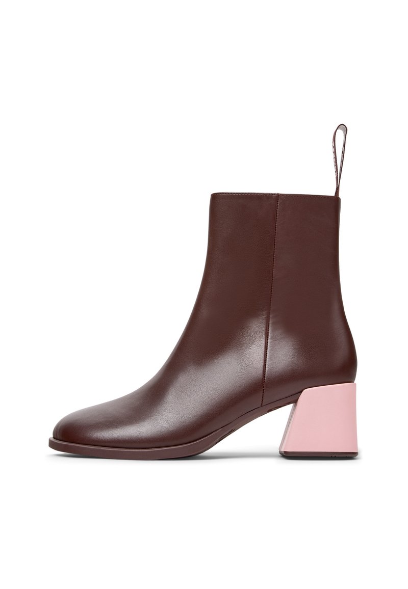 Καφέ δερμάτινη μπότα αστραγάλου με κωνικό σχήμα και αντιθέτου ροζ τετράγωνη σόλα. Απαλή υφή και μινιμαλιστικός σχεδιασμός με βρόχο πίσω.