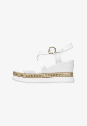 White wedge sandals featuring a wide strap with a buckle, a textured platform with a braided gold accent, and a sturdy rubber sole.