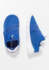 Modré sportovní boty s síťovinovým a textilním svrškem, pružnými pásky, bílými podrážkami a logem na boku. Zaoblený tvar usnadňuje nošení.