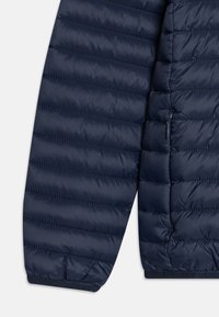 Ärmel einer dunkelblauen Daunenjacke, mit einem gesteppten Design und horizontalen Nähten, glatter Textur und elastischen Bündchen für eine enganliegende Passform.