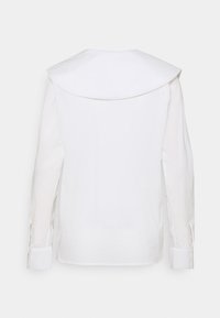 Camicia bianca a maniche lunghe con un ampio colletto arrotondato. Realizzata in tessuto morbido, con polsini con bottoni e spacco ai lati dell'orlo.