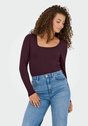 Bodysuit burdeos de manga larga con escote cuadrado, combinado con jeans de tiro alto en azul claro. Textura suave y diseño ajustado.