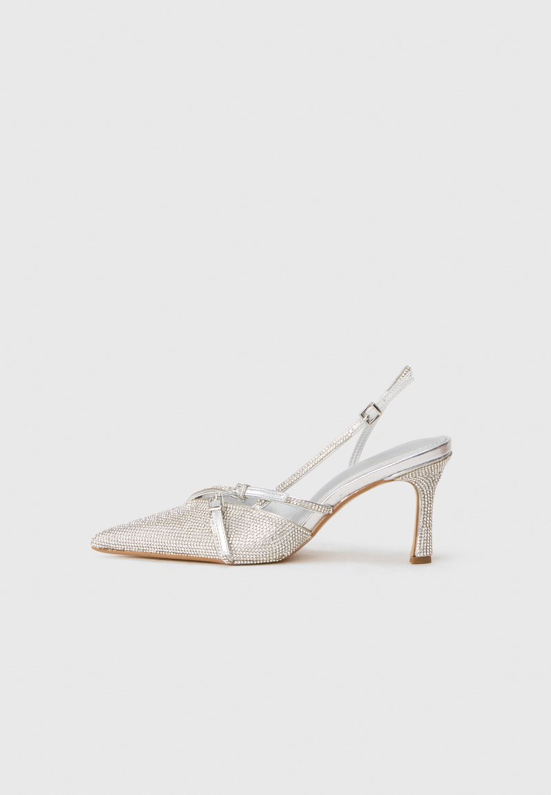 Norādītā pirksta sudraba slingback zābaks ar metāliski spīguļojošu virsmu, grezns ar spīguļojošiem akcentiem un strukturētu papēdi. Platas siksniņas detaļas.