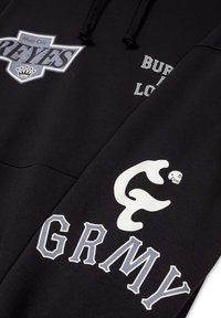 Sudadera negra con gráficos impresos en blanco y gris prominentes. Incluye el texto "Mud City Reyes," "BURN," "LOVE," y "GRMY," con un acento de calavera.