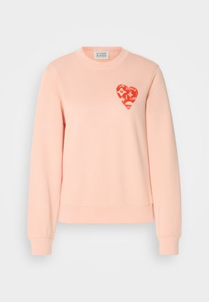Pink sweatshirt made from soft fabric, featuring a ribbed crew neckline and cuffs. A red heart graphic accent on the chest adds detail.