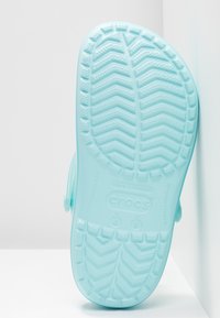 Semelle de Crocs bleu clair avec un motif de semelle texturé et un design en chevron, détails de marque, talon plat et sans embellissements significatifs.