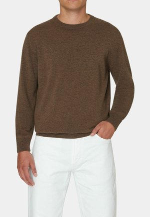 Brązowy dziany sweter z długimi rękawami i okrągłym dekoltem, charakteryzujący się gładką fakturą i ściągaczami przy mankietach, w zestawie z białymi spodniami.