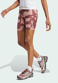 Lightweight, patterned shorts in shades of pink and beige with a side logo. Paired with multi-colored hiking shoes and white ankle socks.
