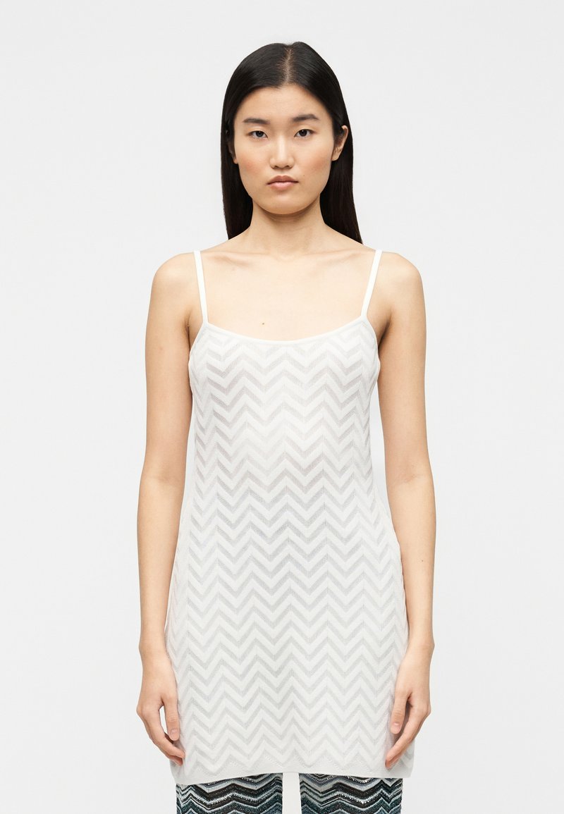 Débardeur blanc léger avec un motif en chevrons, bretelles fines et coupe décontractée, en tissu transparent et texturé.