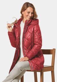 Rode gewatteerde pufferjack met capuchon, voorzien van een rits- en drukknoopsluiting, ribgebreide manchetten en zijzakken. Glad, glanzend stofoppervlak.