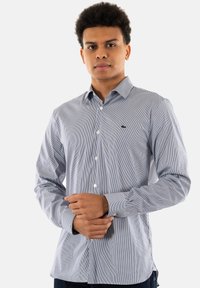 Camicia a righe blu e bianca, tessuto texture, maniche lunghe, vestibilità slim, con un piccolo logo sul petto.