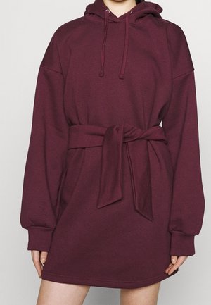Robe sweat à capuche bordeaux avec des manches longues, une ceinture à nouer à la taille et des poignets côtelés. Tissu lisse avec une coupe décontractée.