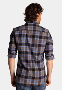 Geruit overhemd met een blauw, oranje en zwart ruitpatroon. Lange mouwen opgerold, klassieke kraag en gebogen zoomontwerp. Katoenen materiaal.