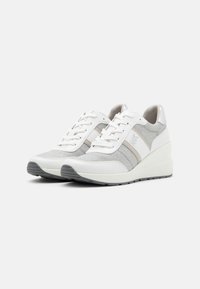 Baskets de sport blanches et grises avec une tige en tissu texturé, fermeture à lacets et semelle en coin. Présente un branding subtil et des détails d'accent.