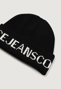 Gorro de malha preto com textura canelada, apresentando letras brancas em contraste na dobra da aba.