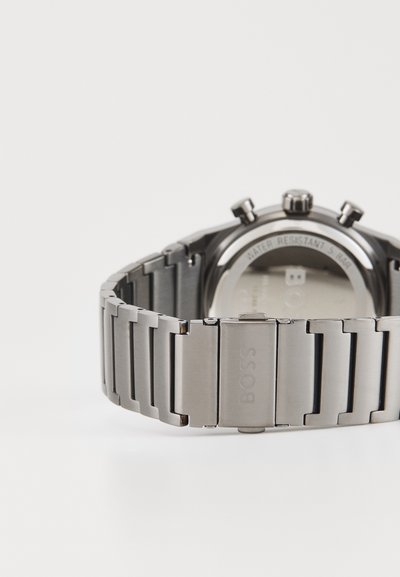 Montre en acier inoxydable avec un fini brossé, dotée d'un bracelet à larges maillons, d'un chronographe à quartz et de poussoirs proéminents sur le côté.