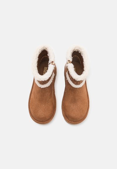 Brown suede ankle boots with a plush white fur collar, gold hardware accents, and a textured surface, featuring a rounded toe design.