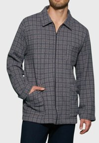 Giacca a quadri grigia con colletto, chiusura con zip, tasche laterali e tessuto testurizzato in un motivo a scacchi. Vestibilità regolare con una tasca sul petto.