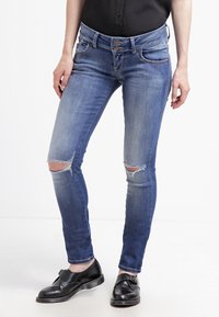 Uppskattade blå denimjeans med smal passform, med hål vid knäna och dubbelknäppt stängning. I kombination med svarta skor.