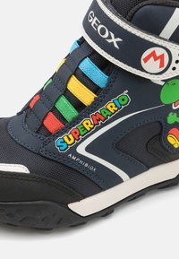 Temno modri otroški škornji z barvitimi elastikami, ki prikazujejo grafiko Super Maria, narejeni iz trpežnega, vremensko odpornega materiala.