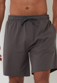 Pantaloni corti in cotone grigi con vita elasticizzata e lacci, dotati di tasche laterali e una vestibilità ampia. Texture liscia, design alla lunghezza del ginocchio.
