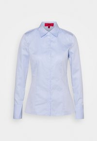 Camicia azzurra a maniche lunghe in cotone, con colletto a punta, chiusura frontale con bottoni e vestibilità su misura con una texture liscia.