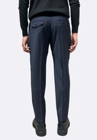 Pantaloni blu navy realizzati in tessuto liscio con vestibilità sartoriale. Presentano due tasche posteriori con chiusura a bottone e un design a gamba dritta.